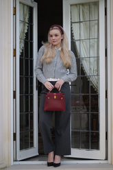 a lady in a white shirt, a grey cardigan and a pair of grey pants